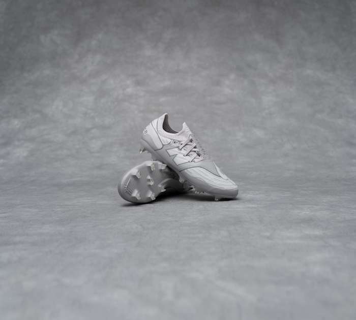 Side view of grey New Balance soccer cleats.